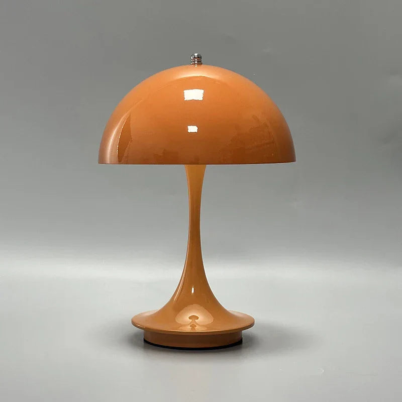 Orange mushroom-shaped table lamp with a domed shade and slender stem.