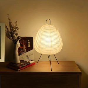 Paper lantern table lamp with a beehive-shaped shade on tripod legs.