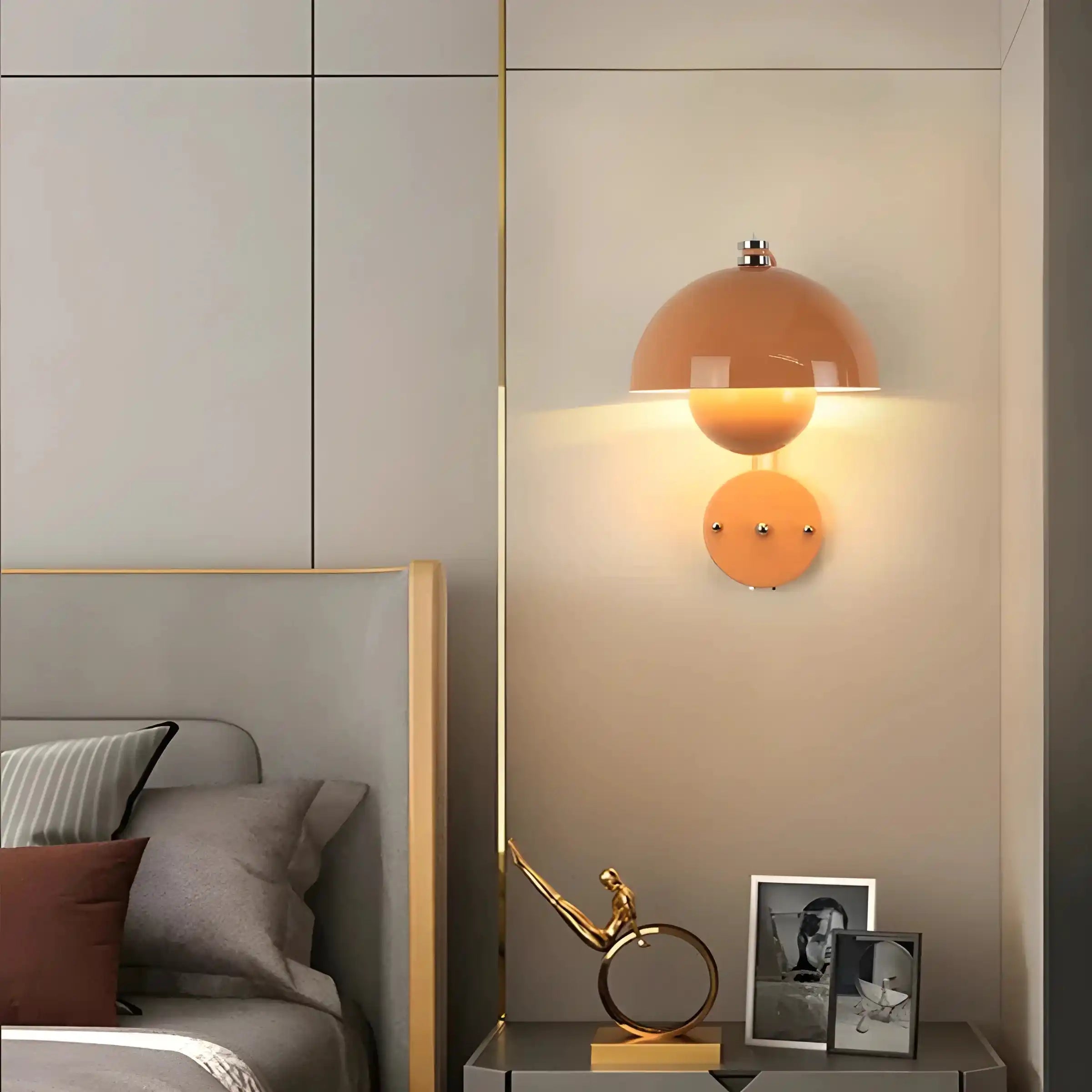 Peach-colored dome wall lamp with a circular base emitting warm light.