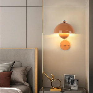 Peach-colored dome wall sconce emitting warm light.