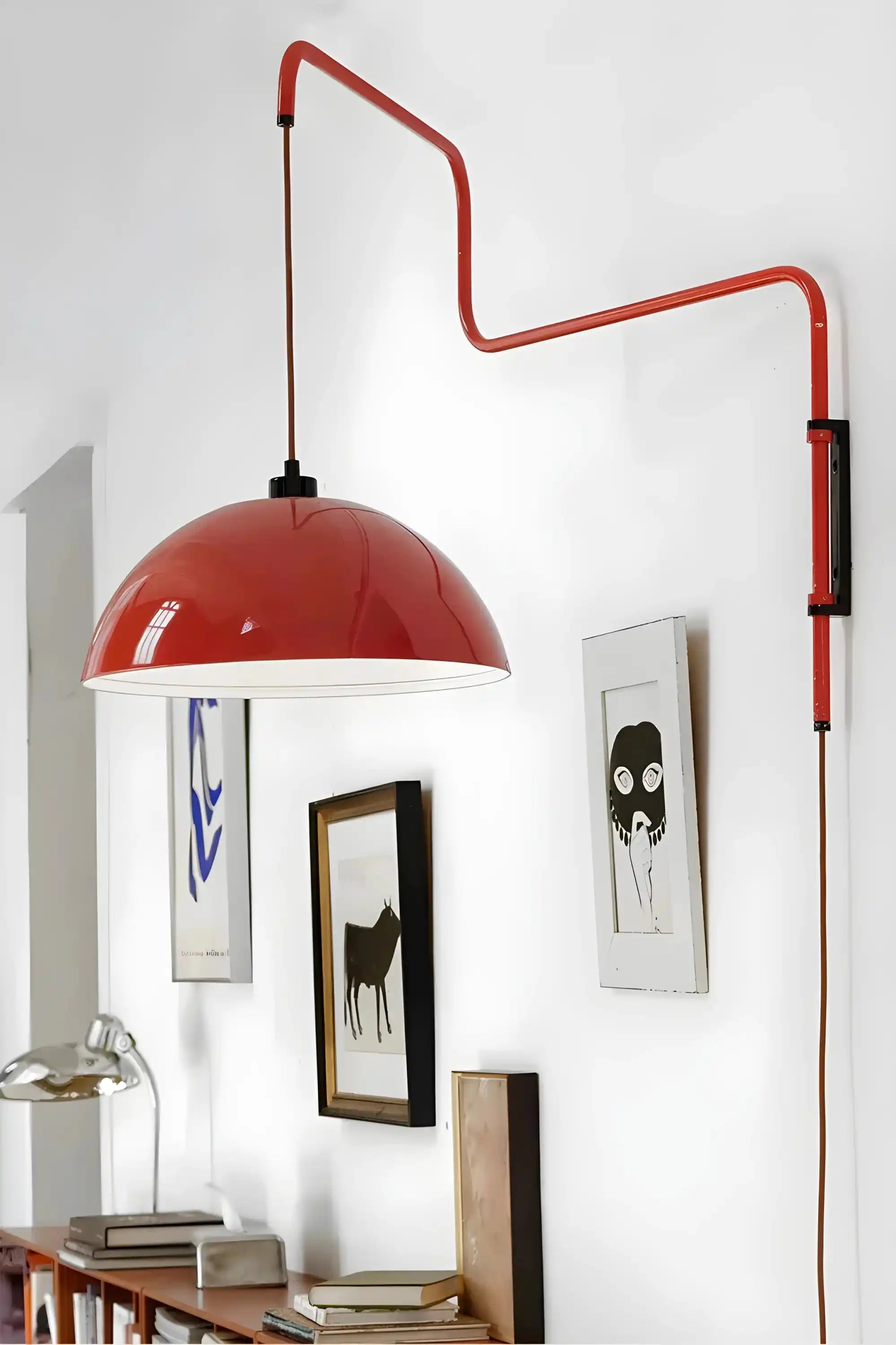 Red dome-shaped pendant lamp with an adjustable wall-mounted arm.