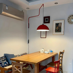 Wooden dining table with chairs and a red pendant lamp above.