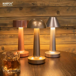 Set of three modern cordless table lamps with metallic shades and glowing bases.