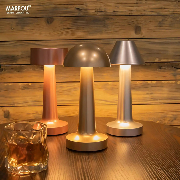 Set of three modern cordless table lamps with metallic shades and warm glowing bases.