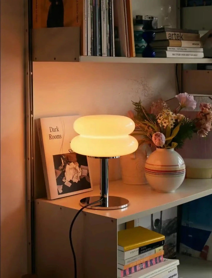 Table lamp with a glowing, round, layered shade on a metal base.