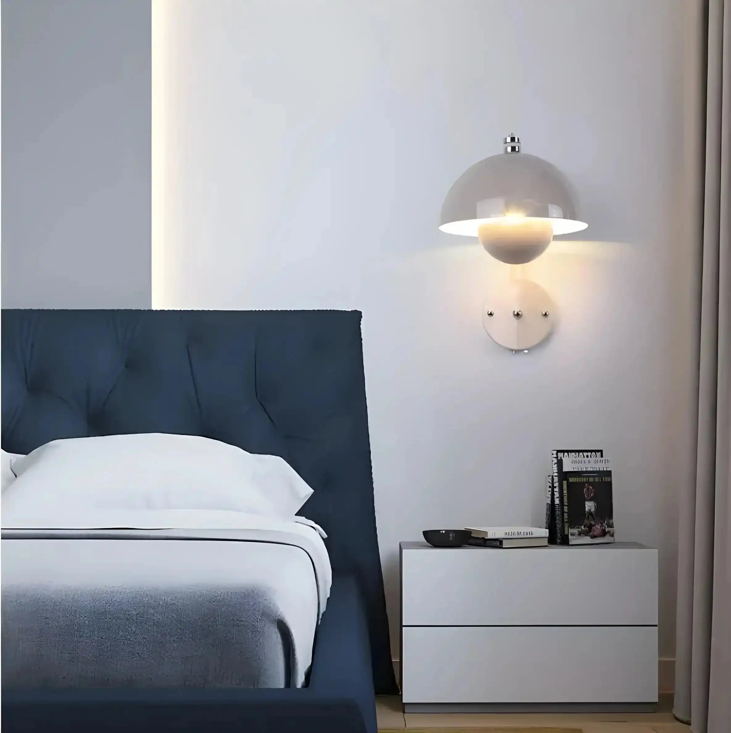 Modern bedroom with a navy blue upholstered headboard and white wall-mounted lamp.